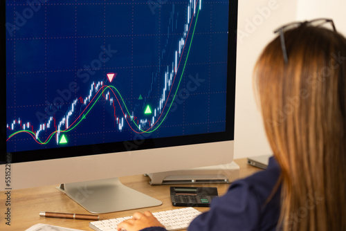 Businesswoman watches stock exchange information and rising stock chart on the screen. Stock market data, financial figures, trading, business, investment, revenues and financial report.