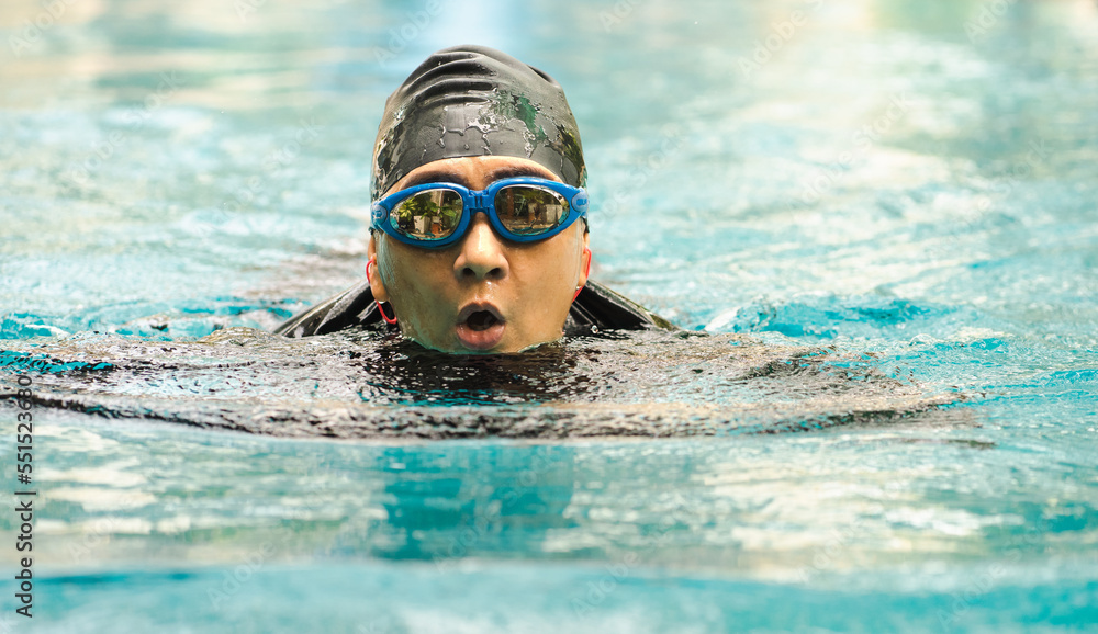 Happy active senior woman has fun swimming in swimming pool. Portrait of Asian female elderly swimmer in swimwear enjoys water sport exercising. Older person leisure activity relaxing and healthy.