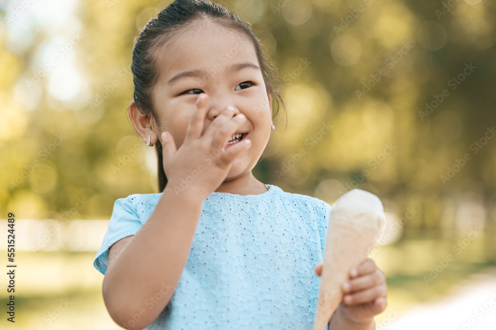 Cute little girl eating ice-cream and looking contented Cute little girl eating ice-cream and looking contented