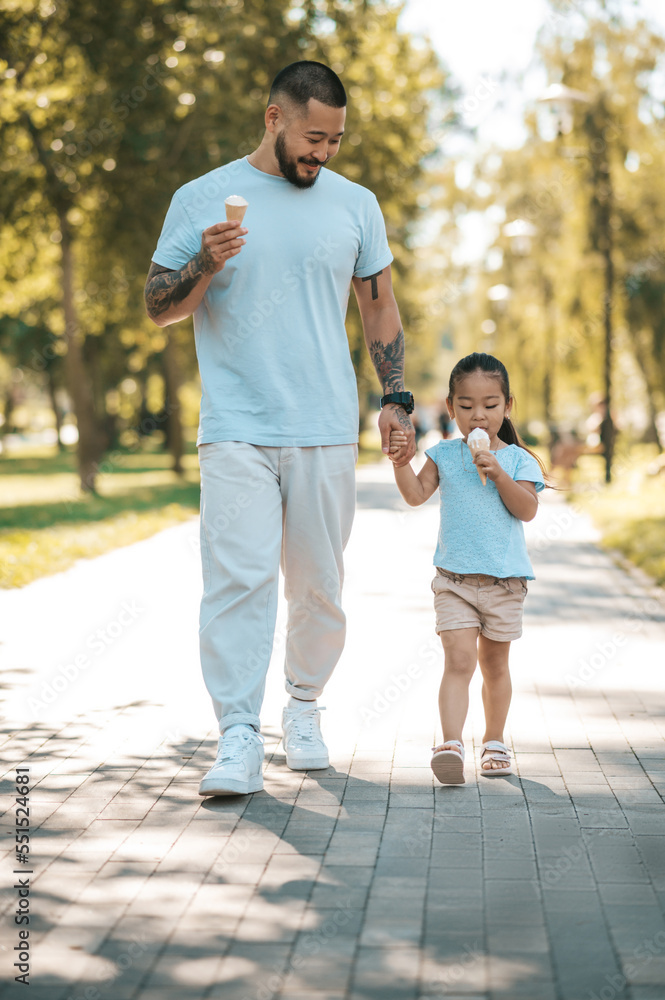 Young dad and his daughter eating ice-cream and looking enjoyed Young dad and his daughter eating ice-cream and looking enjoyed