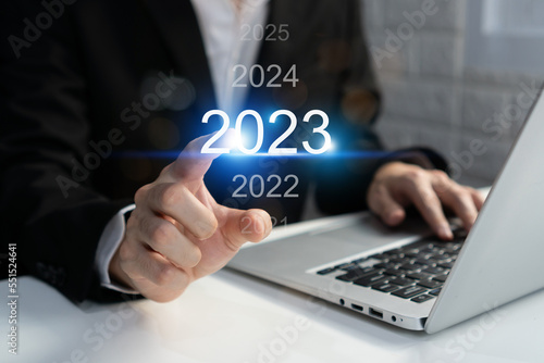 Asian businessman using computer with virtual 2023 year diagram. Business planning, trend change from 2022 to 2023, goals, strategy, investment. Happy new year concept. Closeup and copy space