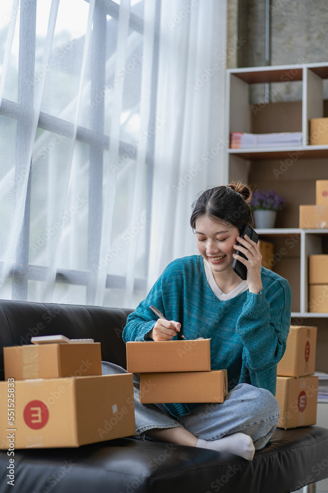 Asian woman taking orders over the phone Online sales, delivery, marketing. Excited young Asian entrepreneurs with digital laptops while working from home. Small business Startup SME Asian woman taking orders over the phone Online sales, delivery, marketing. Excited young Asian entrepreneurs with digital laptops while working from home. Small business Startup SME