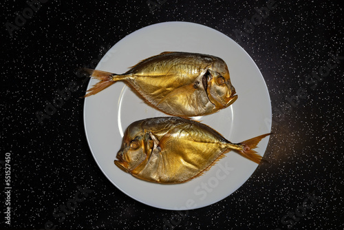 Vomers (Selene peruviana) are a genus of marine fish that belong to the scad family (Carangidae). Two smoked fish on a white plate photo