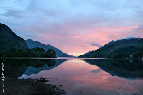 Colourful sunset in the Scottish Highlands with mountains  houses  sky and light reflected off the lake