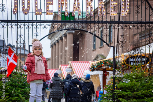 Photography A cute girl holding a danish flag stands in front of a Christmas market in Copen