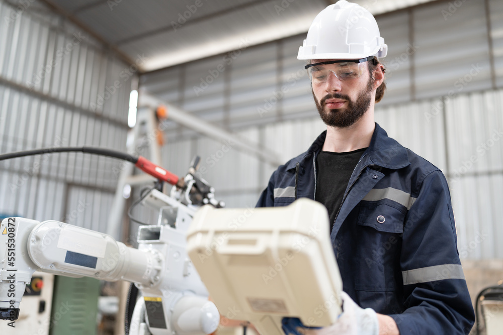 Caucasian technician engineer man use remote control with checking machine arm robot at factory Caucasian technician engineer man use remote control with checking machine arm robot at factory