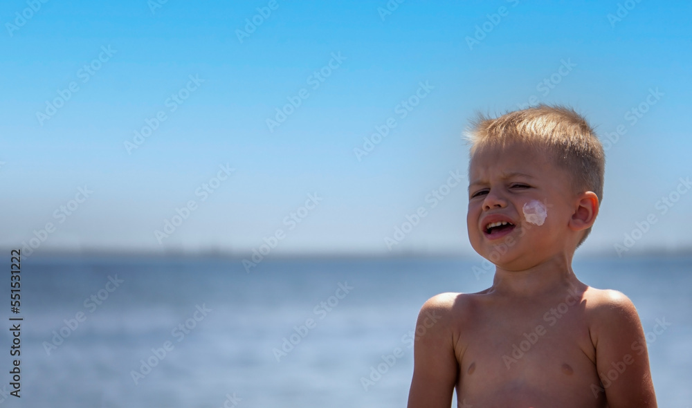 Sunscreen on the child's face and back. On the background of the sea. Sunscreen on the child's face and back. On the background of the sea.