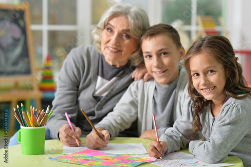 Portrait of grandmother with kids drawing at home