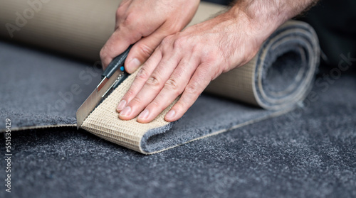 Handyman cutting a new carpet with a carpet cutter...
