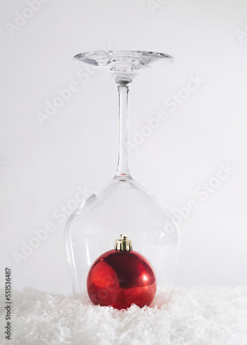 New Year red bauble ornament captured in a wine glass. Snowy winter design idea. Holiday  abstract concept