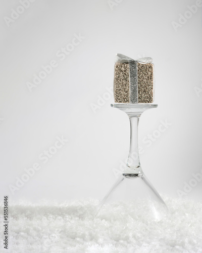 Christmas sparkling gift standing on drinking glass. Holiday winter design idea. New year and holidays concept