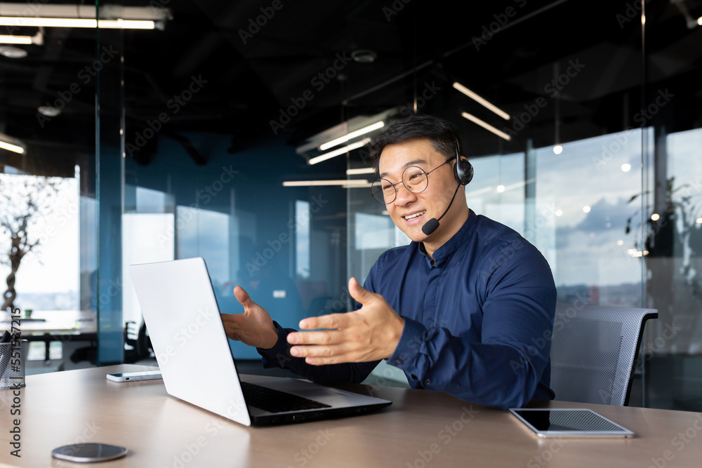 Asian with a headset is talking on video call, man inside office smiling and gesturing joyfully in an online meeting, a businessman is telling his colleagues, a customer service tech support worker. Asian with a headset is talking on video call, man inside office smiling and gesturing joyfully in an online meeting, a businessman is telling his colleagues, a customer service tech support worker.