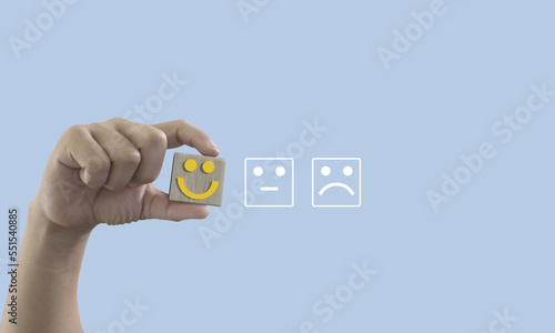 Man hand holding emotion face block, customer satisfaction concept. smiling face, Service rating, ranking, customer review, copy space, satisfaction, evaluation and feedback concept 