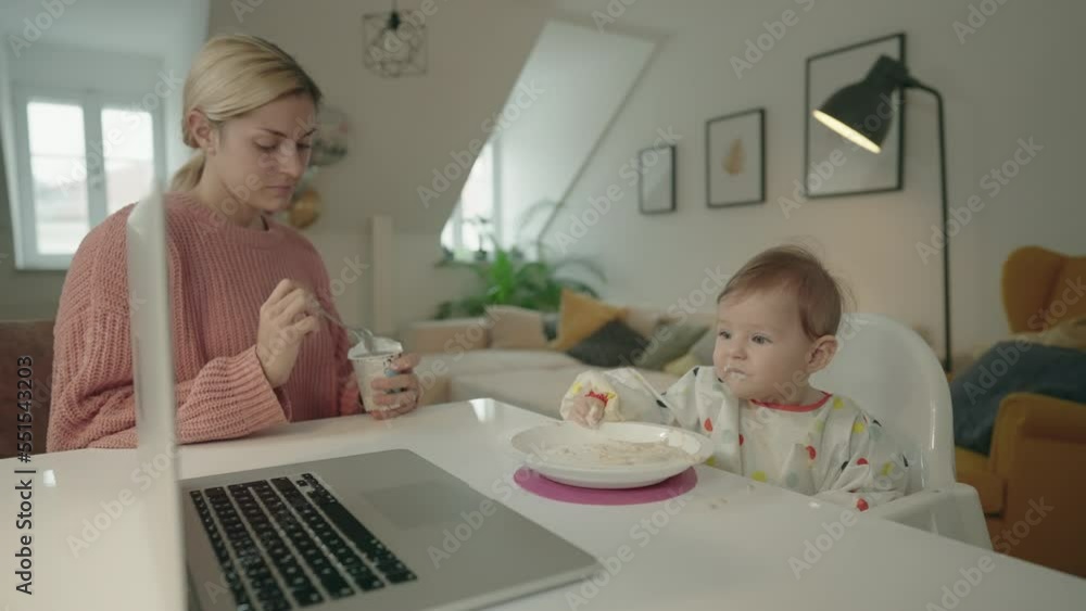Mom feeding her baby at home while the baby watches a cartoon on the computer. Not recommended feeding technique, common parenting problem concept video Mom feeding her baby at home while the baby watches a cartoon on the computer. Not recommended feeding technique, common parenting problem concept video