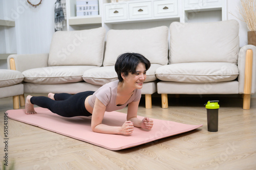 An Asian young woman is workout on fitness mat , exercise at home , healthy lifestyle concept