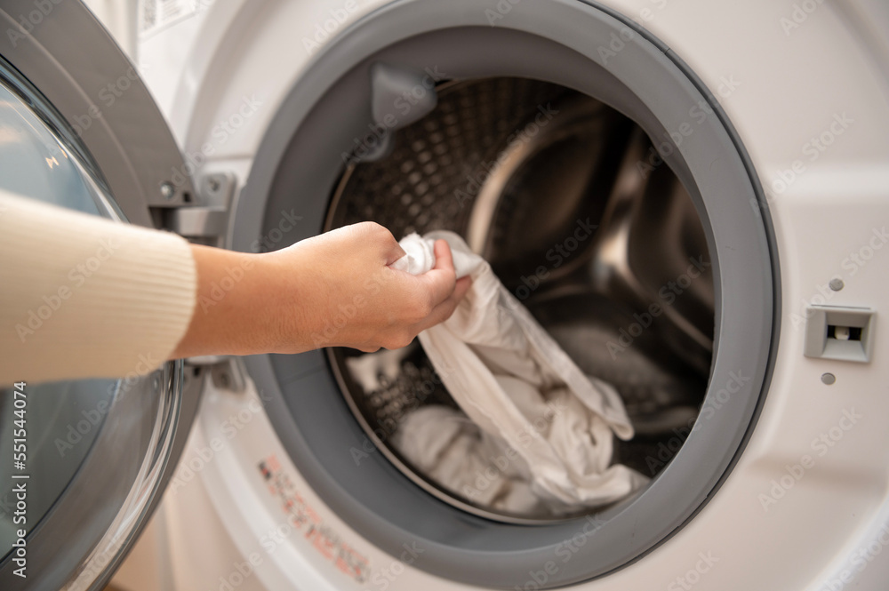 Close-up woman hand is keeping clothes in washing machine , health care lifestyle concept Close-up woman hand is keeping clothes in washing machine , health care lifestyle concept