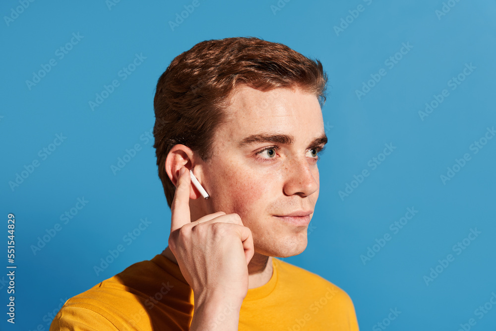 Male meloman touching TWS earbud Male meloman touching TWS earbud