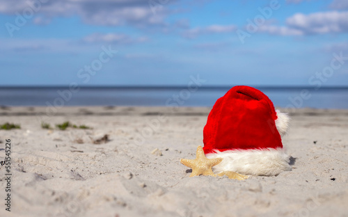 Santa Claus hat and starfish on the sandy beach