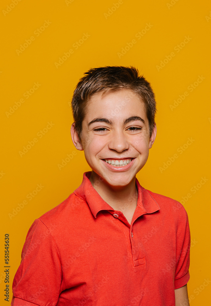 Cheerful boy smiling and looking at camera on yellow background Cheerful boy smiling and looking at camera on yellow background