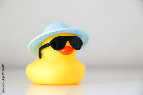 Summer yellow rubber duck wearing black sunglasses and light blue hat. Summer and hot weather concept.