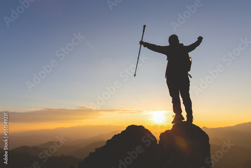 Silhouette of young woman standing alone on top of mountain and raise both arms praying and enjoying nature, Demonstrates hope and freedom, success.