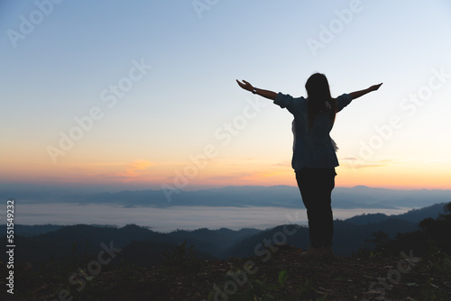 Silhouette of christian young woman praying at sunrise, Freedom and travel adventure concept. Vintage tone filter effect color style.