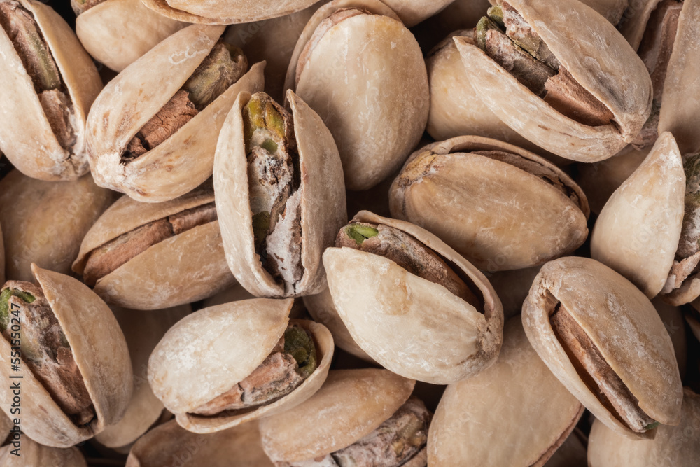 Pistacio nut seeds in shells as a textured background. Close up. Macro shot of pistachios. Dried salted beer snack