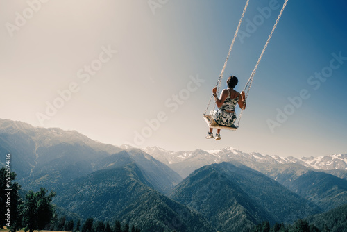 Dream and travel concept, Young beautiful woman happy  on swing flying in the sky over stunning mountain view