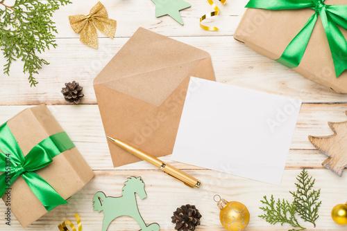 Craft envelope with christmas decoration on wooden background, top view