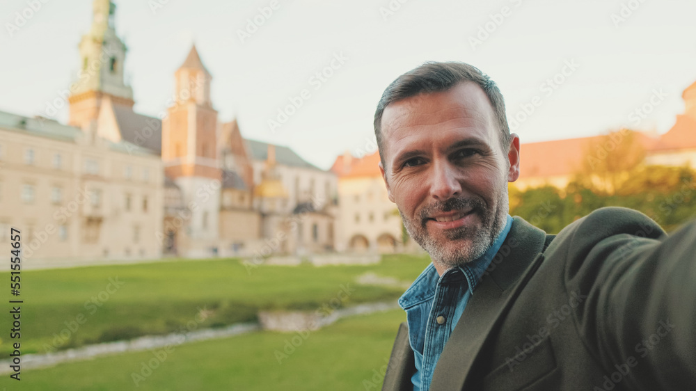 Man takes selfie on mobile phone on the old city background Man takes selfie on mobile phone on the old city background
