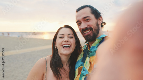 Laughing couple making video call while standing on the beach