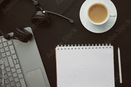 Stylish flat lay office - mock up notebook, cup of coffee, laptop and headphones. New Year resolutions and goals concept.
