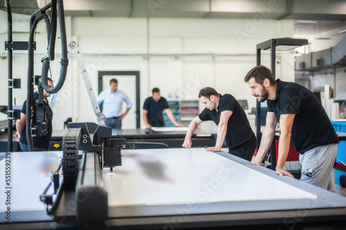 Professional workers graphic technicians operators work in a printing press and print shop with many different types of machines