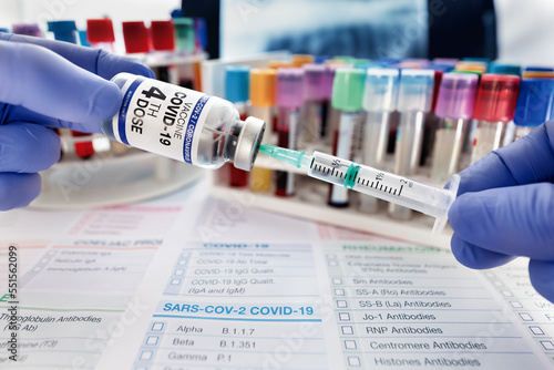 Technician holding COVID-19 vaccine vial for vaccination booster shot for omicron variant. Doctor prepares a dose Coronavirus vaccine for new variants of Sars-cov-2 virus  photo