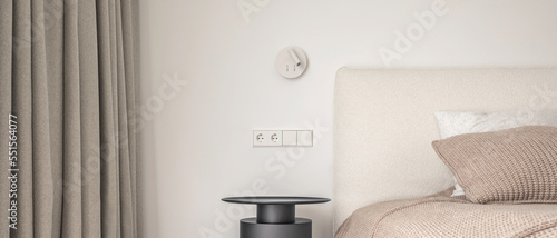 White wall lamp above the bed, metal beside table, white electrical outlet, oak wooden floor..Modern minimalist aesthetic bedroom interior design in warm shades