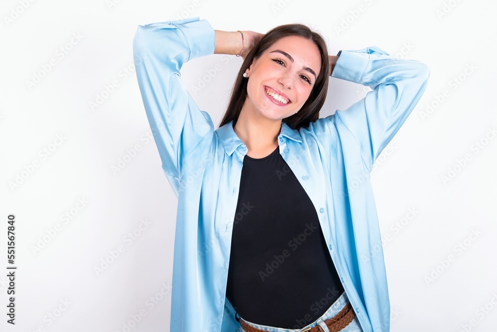 Young caucasian woman wearing blue overshirt over white background stretching arms, relaxed position.