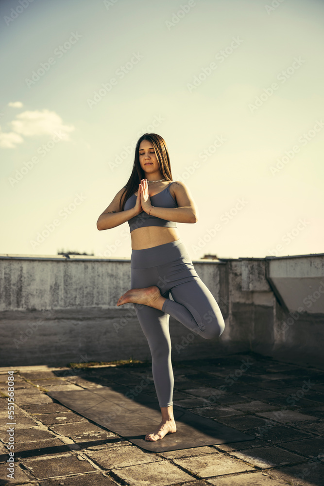 Obraz premium Woman Doing Yoga Outdoors On A Rooftop Terrace