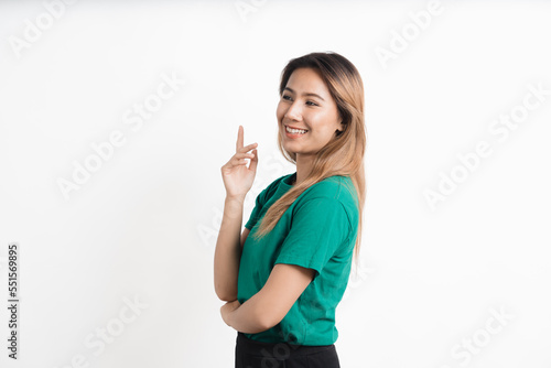 Young asian woman pointing at your product and looks at it isolate on white background.