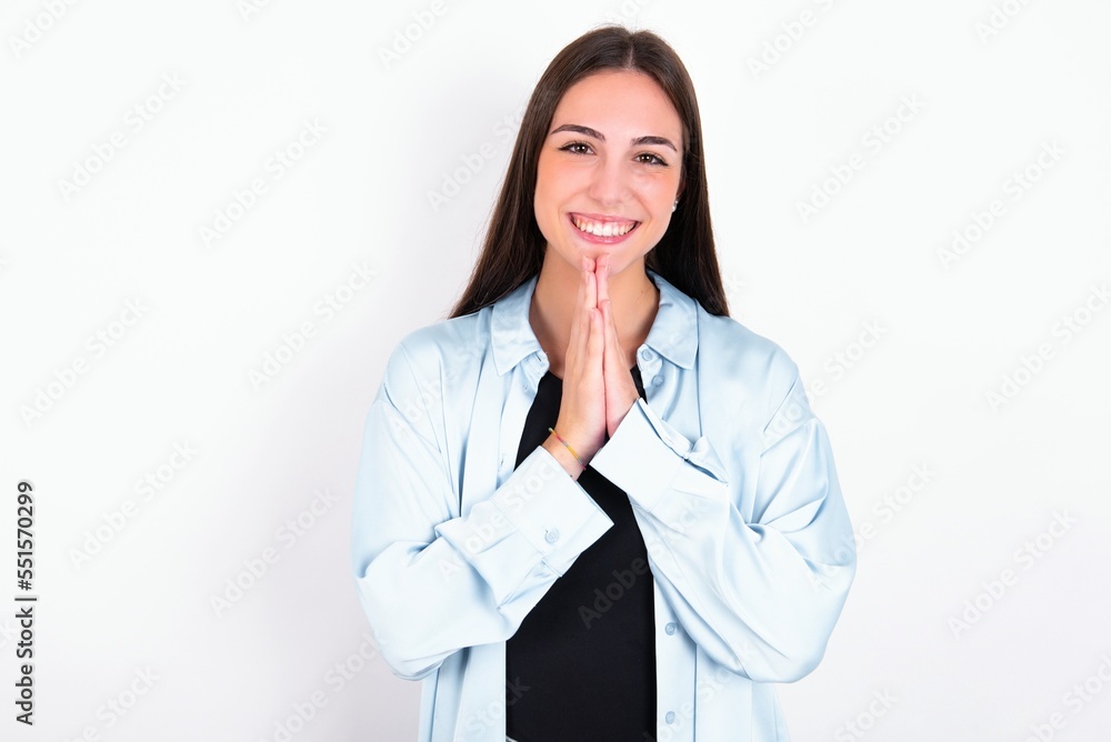 Young caucasian woman wearing blue overshirt over white background praying with hands together asking for forgiveness smiling confident. Young caucasian woman wearing blue overshirt over white background praying with hands together asking for forgiveness smiling confident.