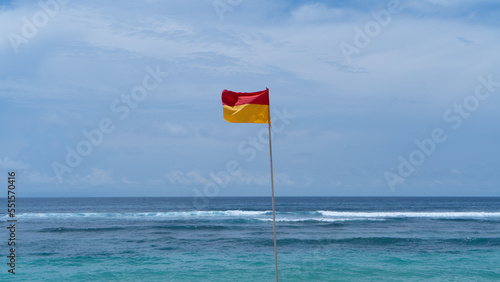 beach safety flag over a blue sky and ocean background 