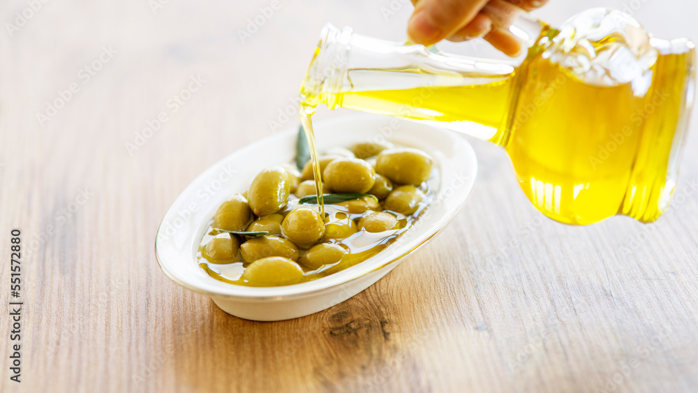 Olive oil and olive berries are on the wooden table Olive oil and olive berries are on the wooden table