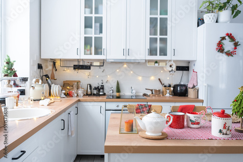 Festive Christmas decor in white kitchen, festive breakfast, white scandi interior. Araucaria as a Christmas tree is decorated and wrapped in a scarf and felt planters. New Year, mood, cozy home