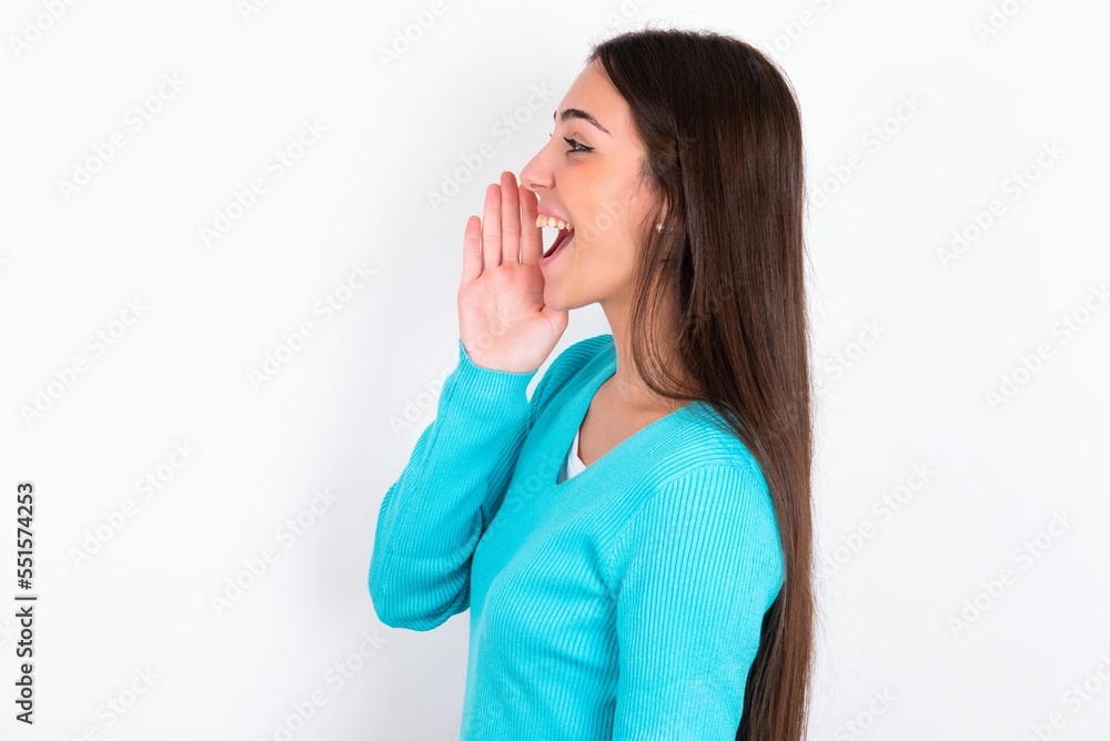 Young caucasian woman wearing blue sweater over white background look empty space holding hand face and screaming or calling someone. Young caucasian woman wearing blue sweater over white background look empty space holding hand face and screaming or calling someone.