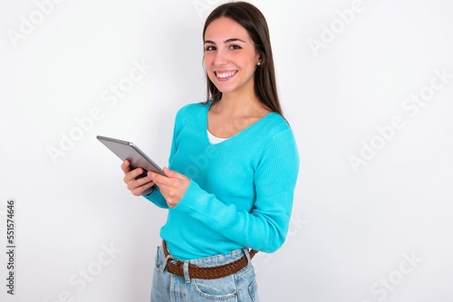 Photo of optimistic Young caucasian woman wearing blue sweater over white background hold tablet