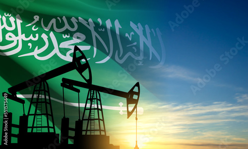 Silhouette of Oil pump on background of flag of Saudi Arabia against the sunset or sunrise
