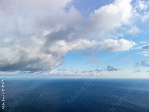 Aerial view. The drone flies over foggy and fluffy clouds. Blue sky sun and sea fog. Abstract aerial nature summer ocean sunset sea and sky background. Horizon. Vacation, travel and holiday concept