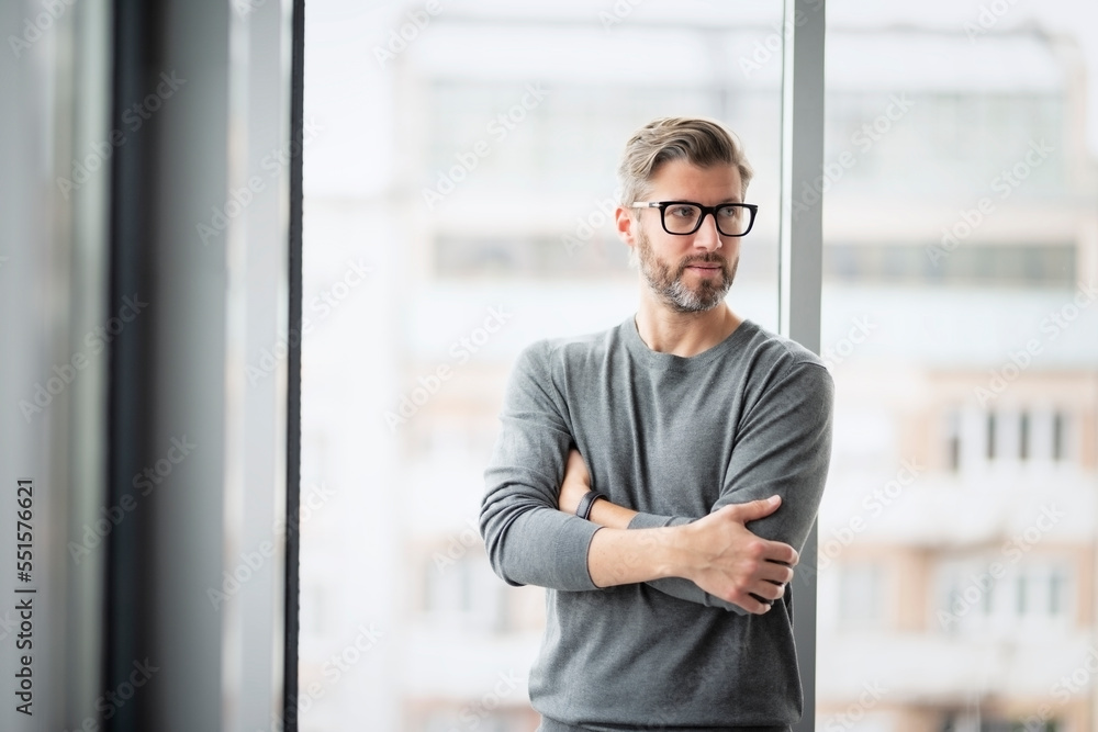 Confident businessman with arms crossed standing at the office Confident businessman with arms crossed standing at the office