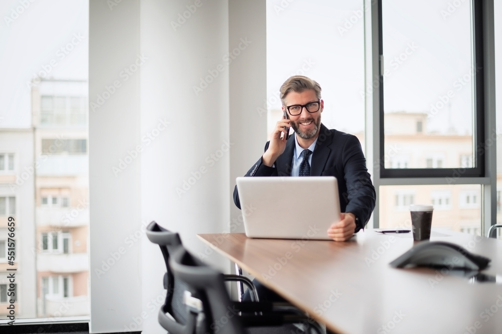 Executive businessman having a call and using laptop while working at the office Executive businessman having a call and using laptop while working at the office
