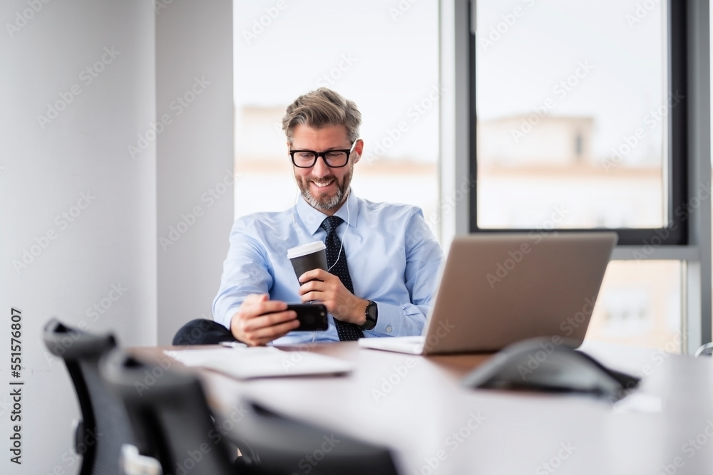 Professional businessman using cellphone and laptop while sitting at the office Professional businessman using cellphone and laptop while sitting at the office