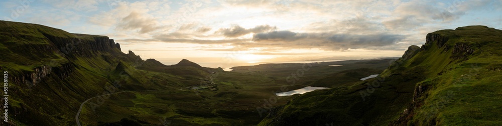 Obraz premium Panoramic shot of Quiraing on Isle of Skye in Scotland under cloudy blue sky at sunrise.